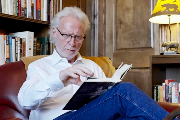 A-man-sitting-in-a-library-reading-a-book