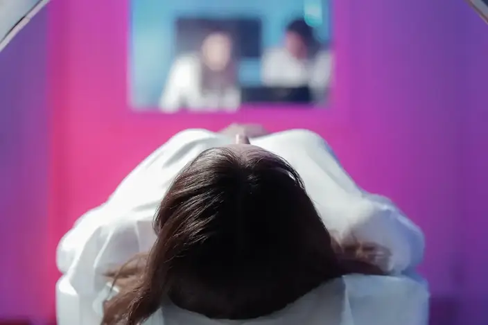 a woman in a white shirt is sitting in a mri