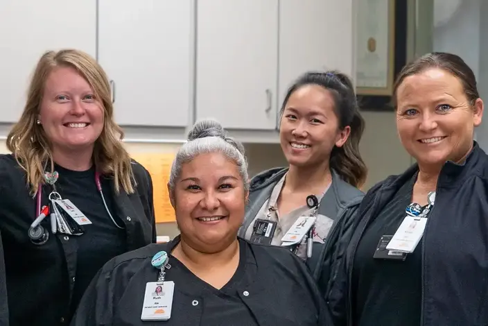 four woman in scrubs smiling