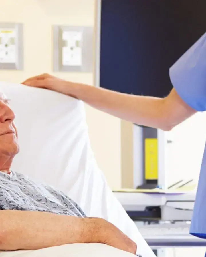 nurse talking to elderly patient in bed